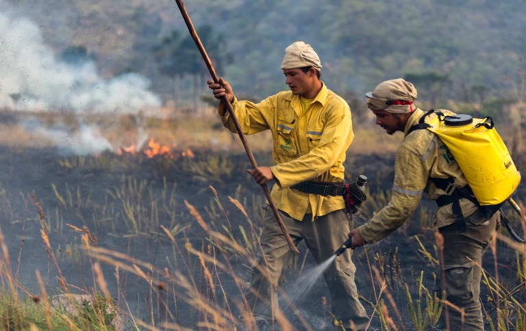 Imagem de dois homens combatendo focos de incêndio